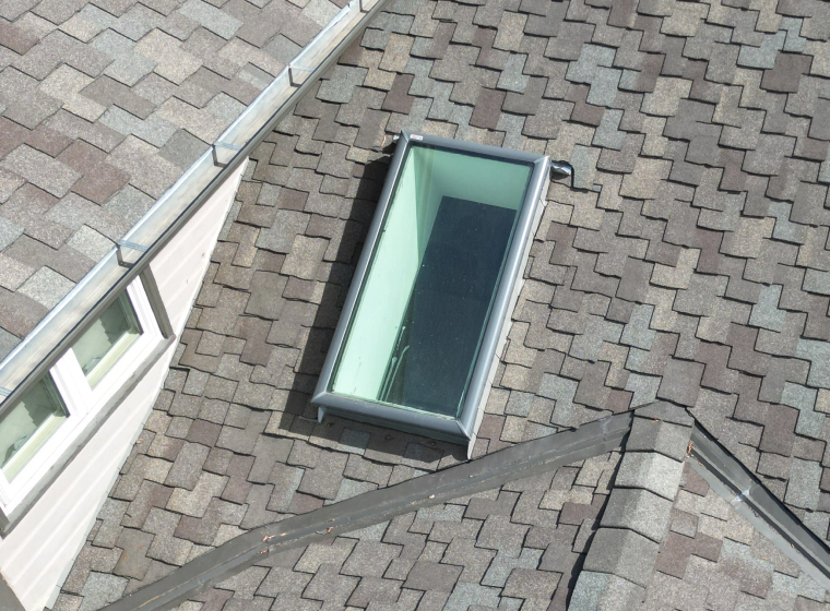 glass skylight window on a grey and brown roofing